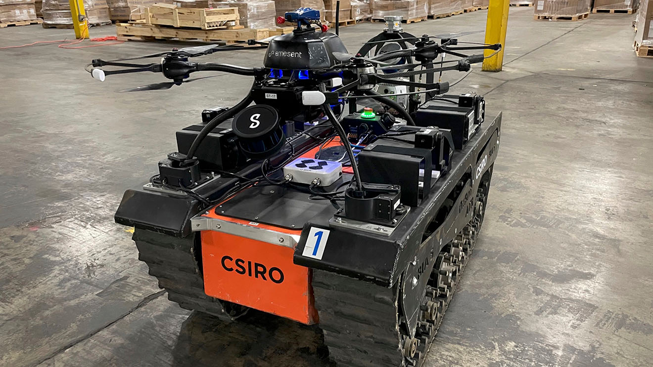 A black autonomous robotic vehicle with tank-like treads and orange 'CSIRO' branding.