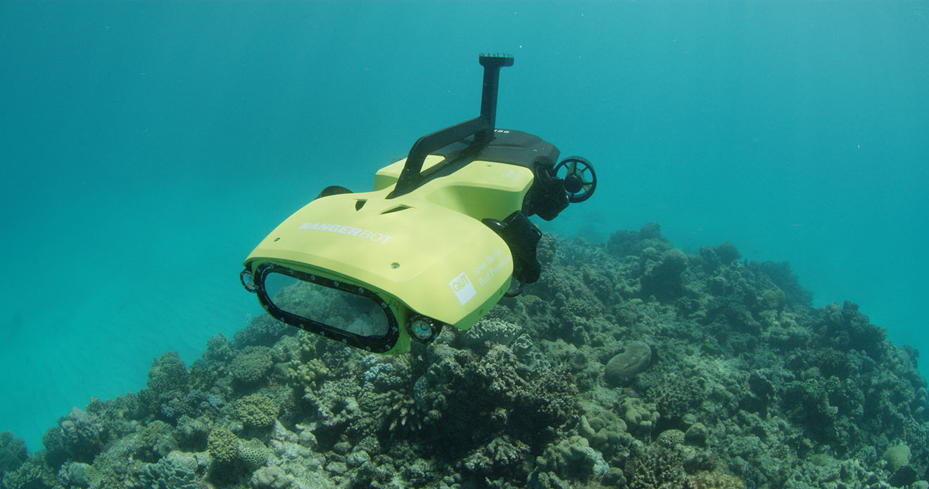 A small yellow submersible robot inspecting a coral reef.