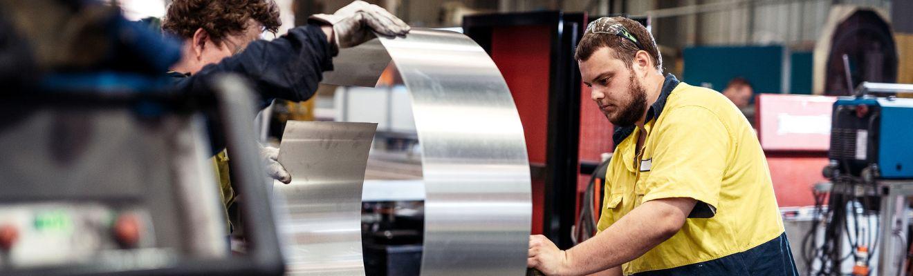 Photo of manufacturing workers working with metal in a factory.