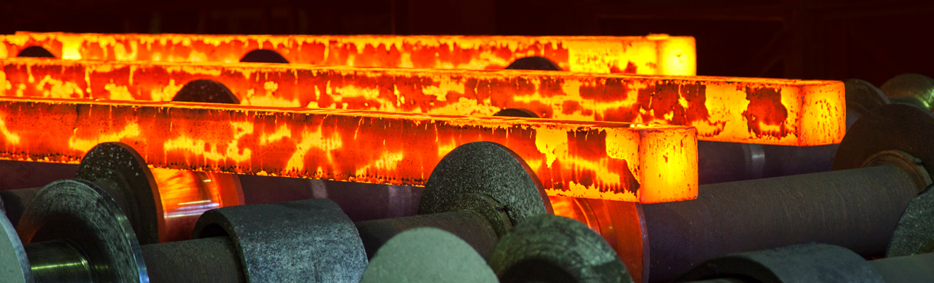 Photo of red-hot steel rods being processed in a steel mill