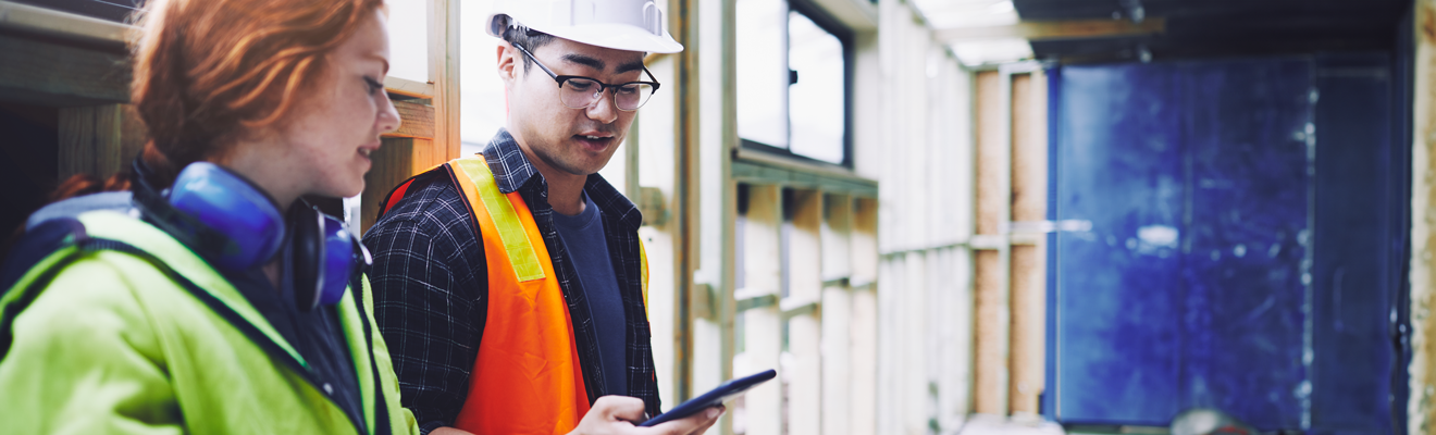 Two workers from diverse backgrounds on a construction site looking at a mobile device