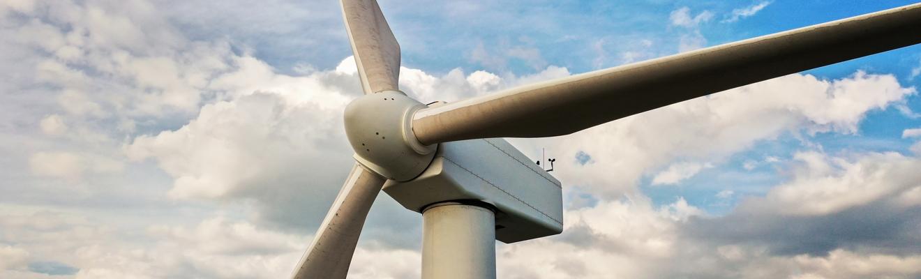 Wind turbine against a blue sky with clouds.