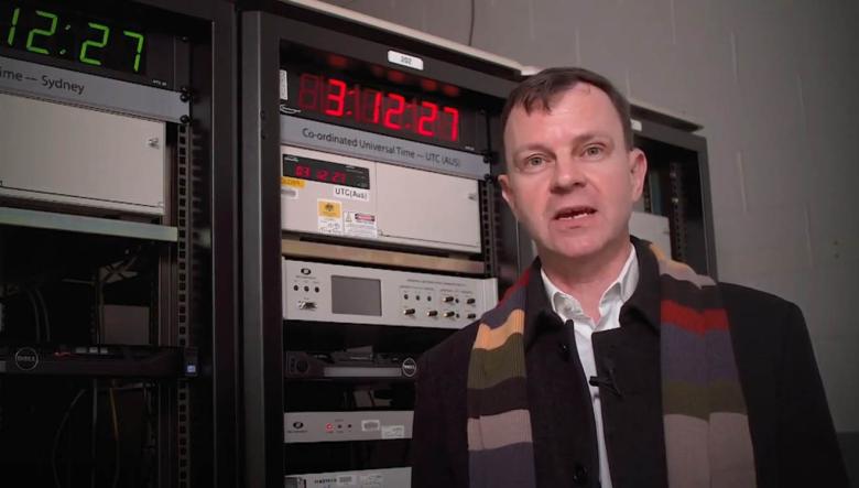 Photo of Chief Metrologist in front of an atomic clock