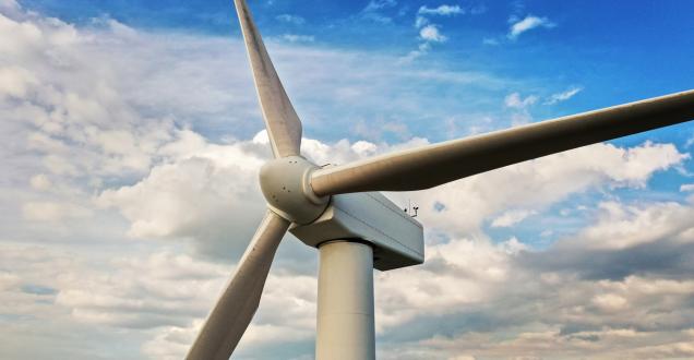 Wind turbine against a blue sky with clouds.