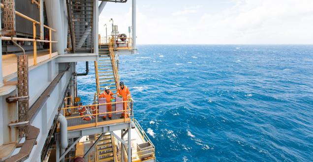 2 workers in fluro orange  on an oil rig in the ocean