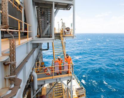 2 workers in fluro orange  on an oil rig in the ocean